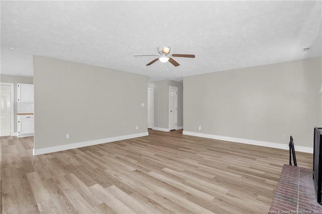 unfurnished living room featuring a textured ceiling, baseboards, a ceiling fan, and light wood-style flooring