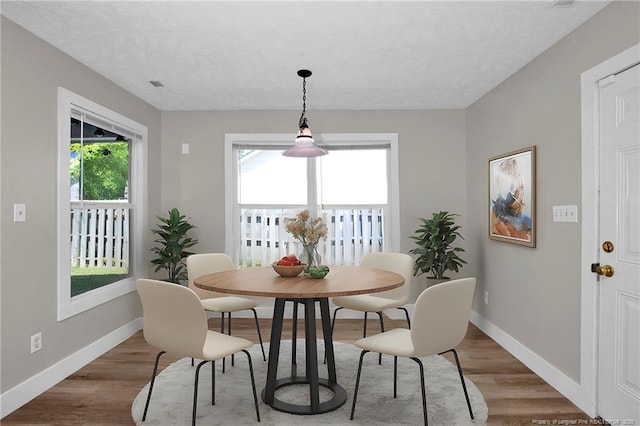 dining room with a textured ceiling, baseboards, and wood finished floors