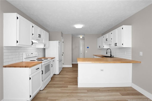 kitchen with butcher block countertops, a sink, baseboards, and white appliances