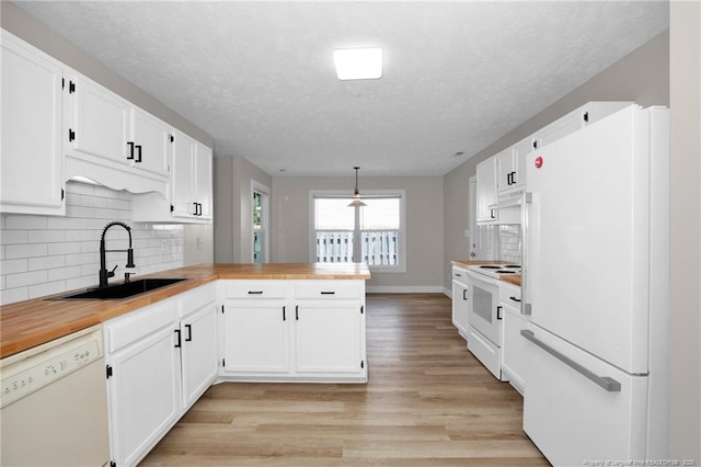 kitchen featuring a sink, light wood-style floors, white appliances, a peninsula, and white cabinetry