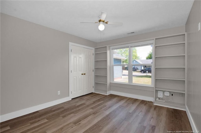 unfurnished room with baseboards, wood finished floors, and visible vents