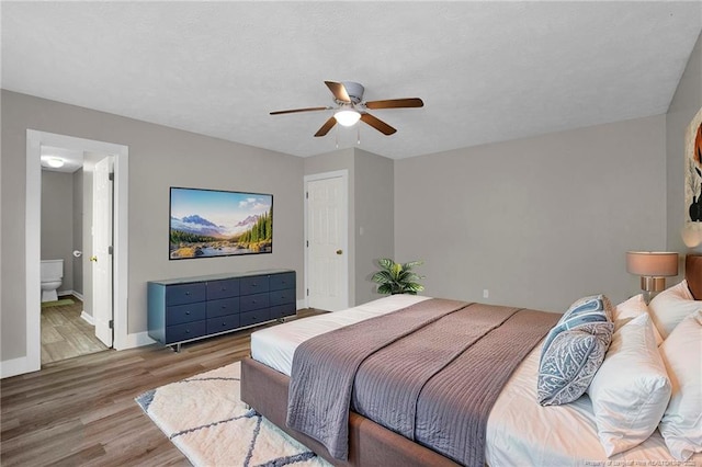 bedroom featuring connected bathroom, baseboards, ceiling fan, and wood finished floors