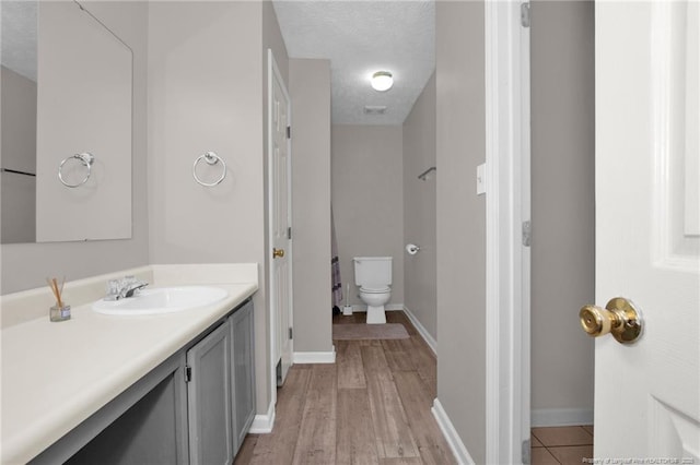 bathroom with toilet, baseboards, wood finished floors, and vanity