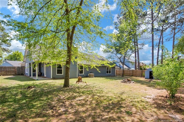 view of yard with a storage unit, an outdoor fire pit, a fenced backyard, and an outbuilding