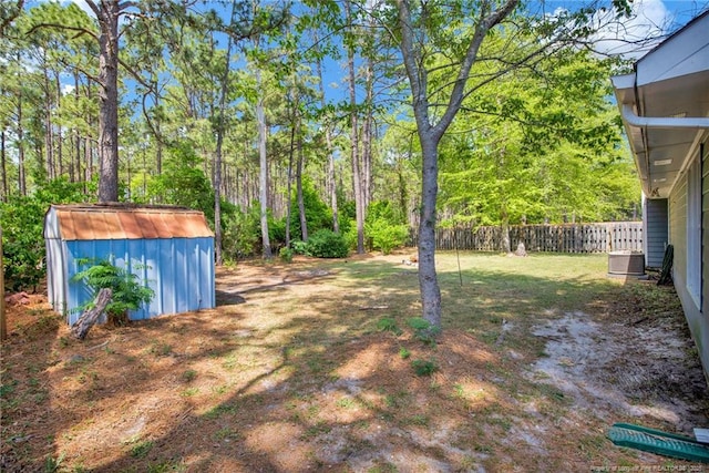 view of yard featuring a storage unit, an outdoor structure, central AC, and fence