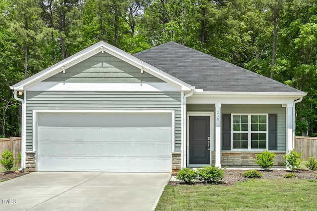 view of front of home featuring fence, a garage, stone siding, and driveway