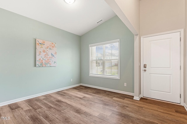 interior space with lofted ceiling, baseboards, visible vents, and wood finished floors