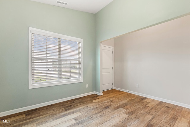unfurnished room featuring baseboards, a healthy amount of sunlight, visible vents, and wood finished floors
