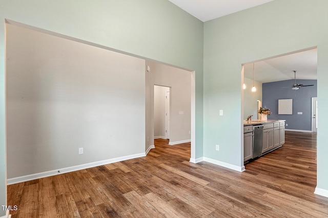 unfurnished living room featuring baseboards, a ceiling fan, and wood finished floors