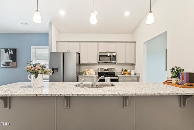 kitchen with hanging light fixtures, stainless steel appliances, a kitchen breakfast bar, and a sink