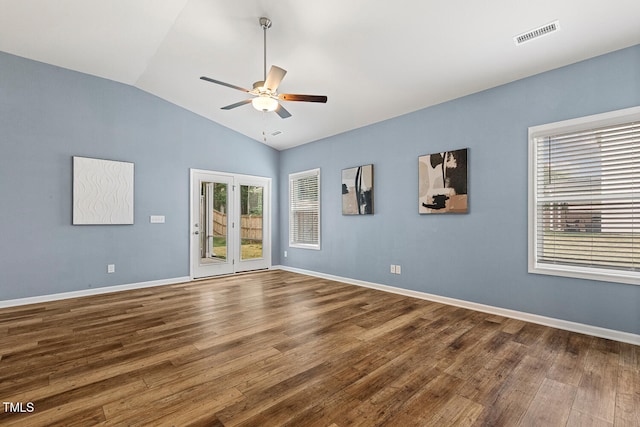 empty room with wood finished floors, a ceiling fan, visible vents, baseboards, and lofted ceiling