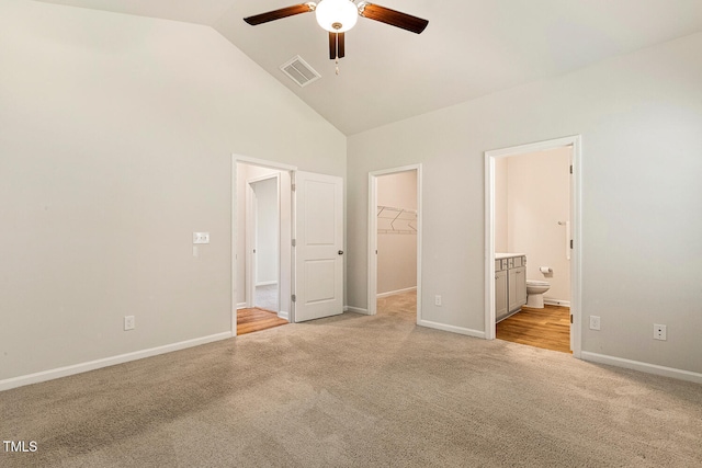 unfurnished bedroom with ensuite bathroom, light colored carpet, visible vents, a spacious closet, and baseboards