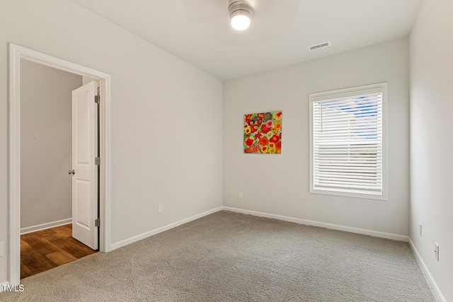 unfurnished room with carpet flooring, visible vents, and baseboards