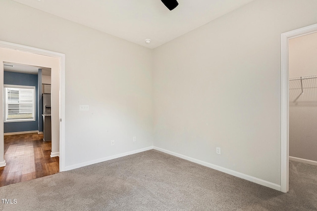unfurnished bedroom with a closet, a spacious closet, carpet floors, a ceiling fan, and baseboards