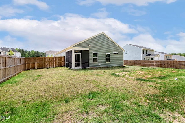 rear view of house featuring a yard, a sunroom, and a fenced backyard