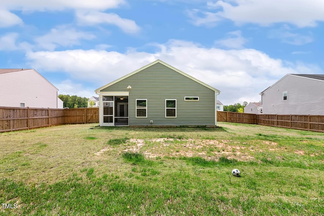 rear view of property with a sunroom, a lawn, and a fenced backyard