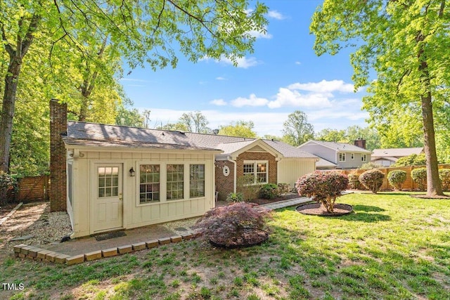 view of front of property with fence, a front lawn, brick siding, board and batten siding, and a chimney