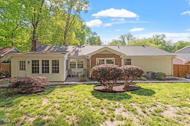 rear view of house with a lawn, fence, a chimney, and central AC unit