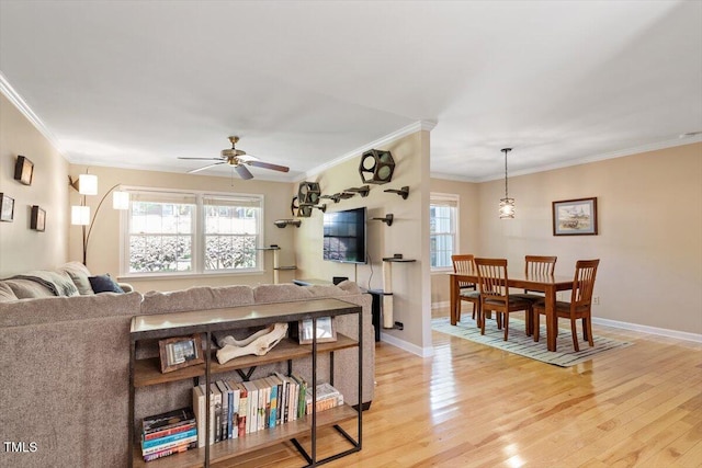 living room with a ceiling fan, baseboards, ornamental molding, and light wood finished floors
