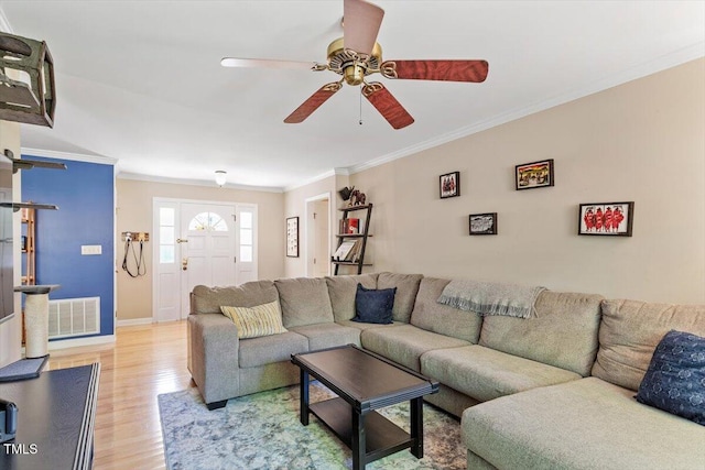 living area featuring ceiling fan, baseboards, light wood-type flooring, visible vents, and ornamental molding