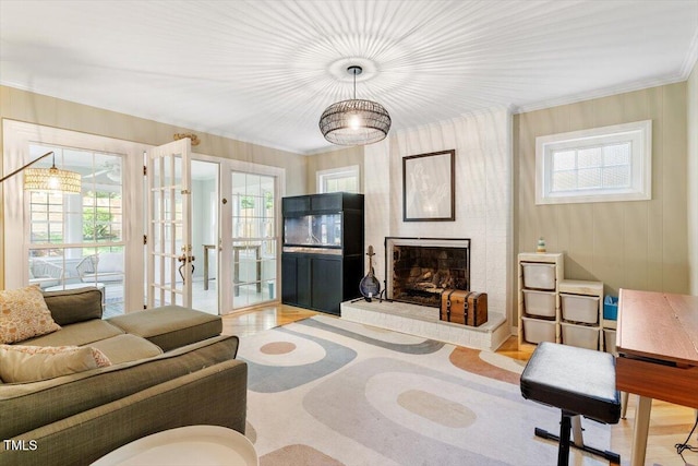 living area with crown molding, a wealth of natural light, a fireplace, and french doors