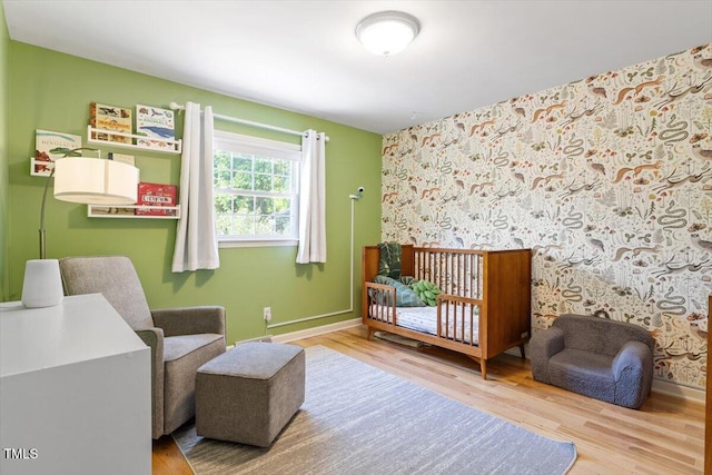bedroom with baseboards, wood finished floors, and wallpapered walls