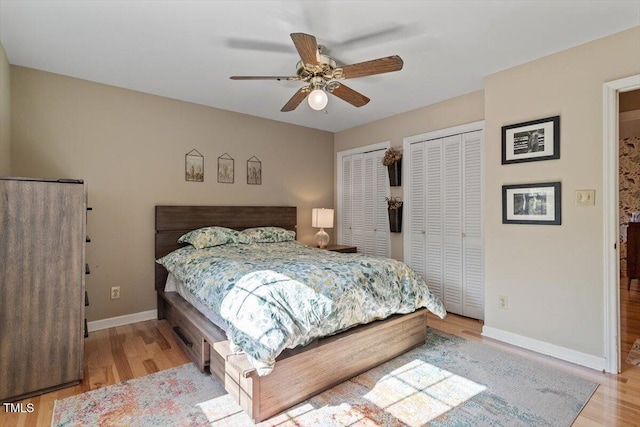 bedroom featuring ceiling fan, multiple closets, baseboards, and wood finished floors