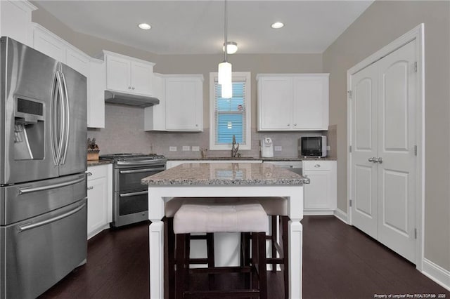 308 Wishaw Ct, Hope Mills, NC 28348 - kitchen featuring appliances with stainless steel finishes, light stone counters, white cabinetry, decorative backsplash, and under cabinet range hood