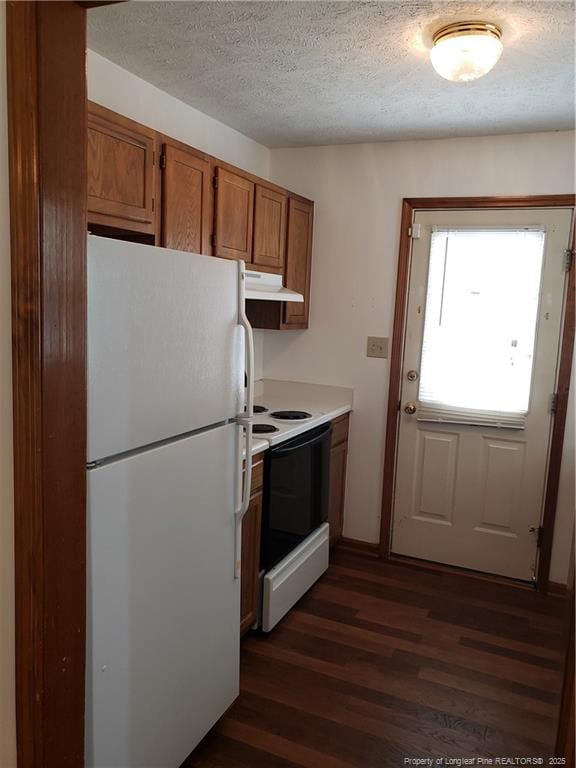 kitchen featuring brown cabinetry, freestanding refrigerator, dark wood-type flooring, a textured ceiling, and range with electric cooktop