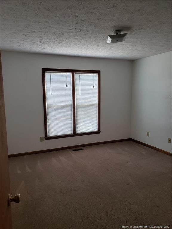 unfurnished room with baseboards, carpet flooring, and visible vents