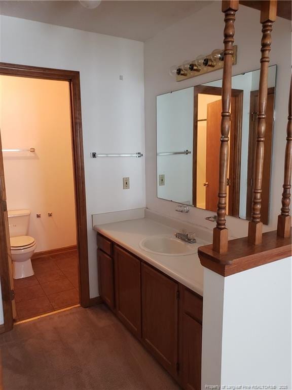 bathroom with vanity, tile patterned flooring, baseboards, and toilet