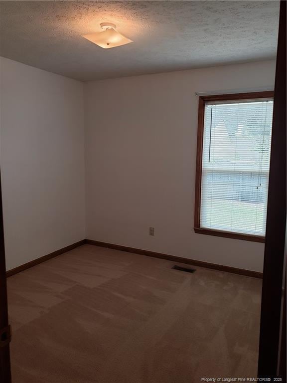 carpeted spare room featuring visible vents, a textured ceiling, and baseboards