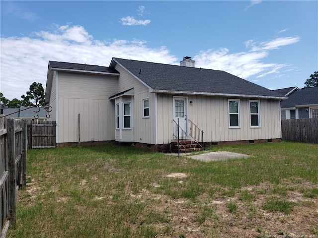 rear view of property featuring crawl space, entry steps, a fenced backyard, a chimney, and a lawn