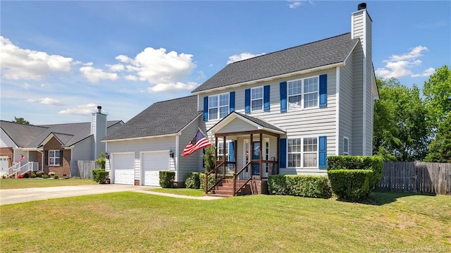 colonial-style house with driveway, a chimney, a garage, fence, and a front lawn