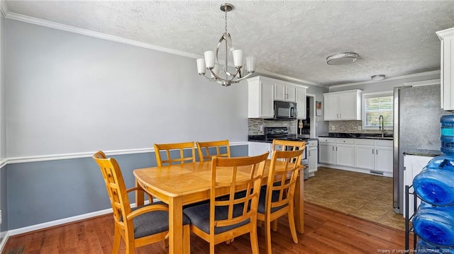 dining area featuring a textured ceiling, an inviting chandelier, ornamental molding, and dark wood finished floors
