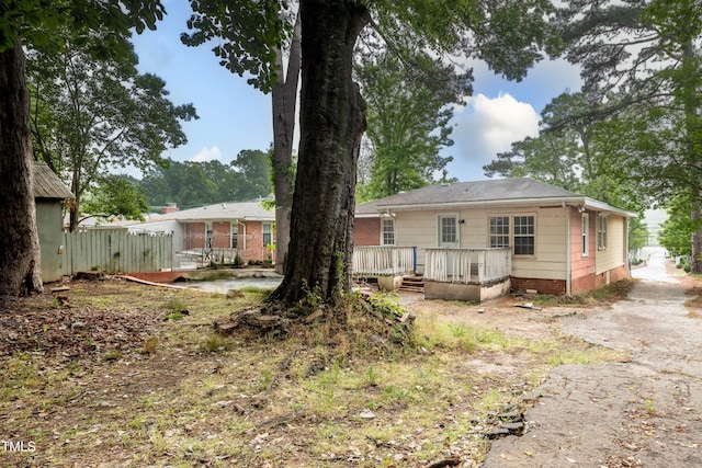 back of property featuring a deck and fence