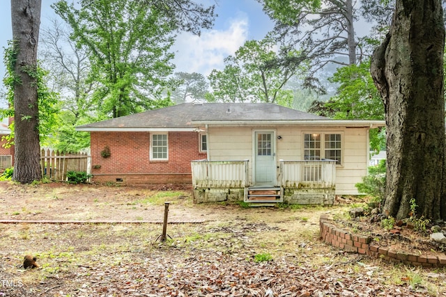 rear view of house featuring fence, a deck, and brick siding