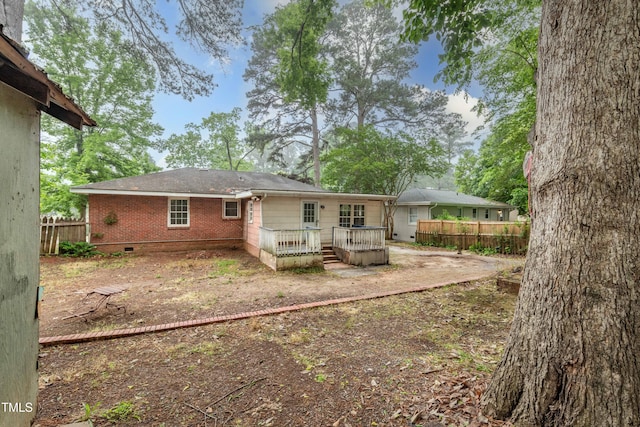 back of property with fence, a wooden deck, crawl space, and brick siding