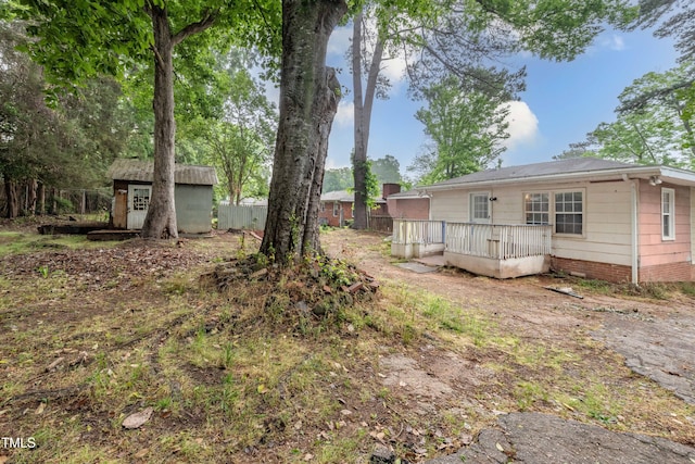 view of yard with a shed, a deck, fence, and an outbuilding