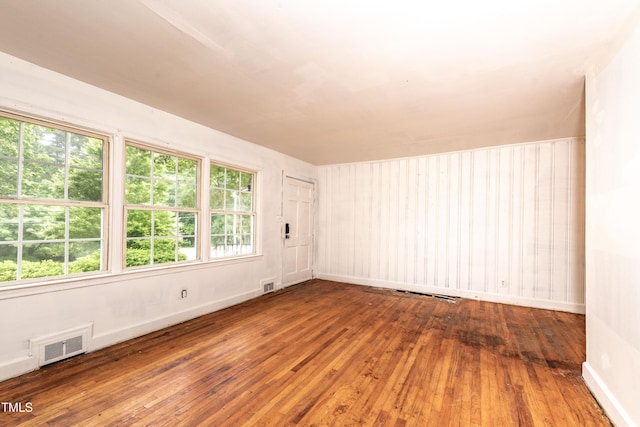 spare room featuring wood-type flooring and baseboards