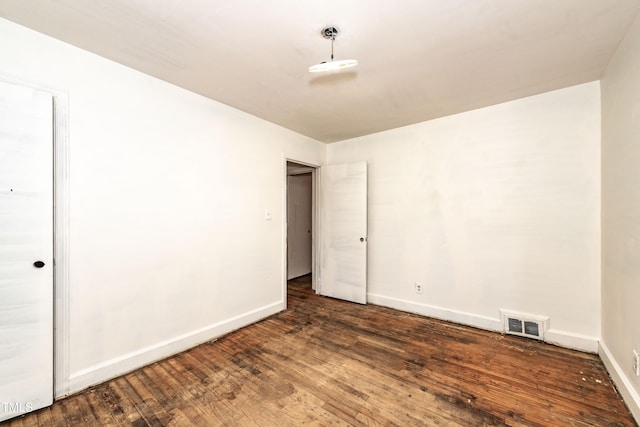 spare room with baseboards and dark wood-type flooring