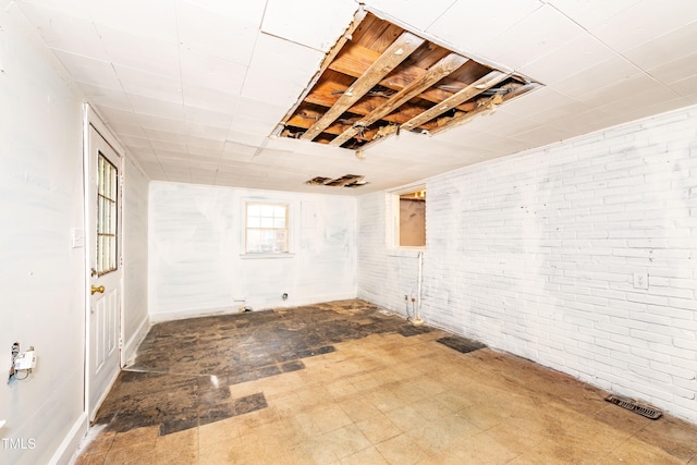 basement featuring brick wall and baseboards