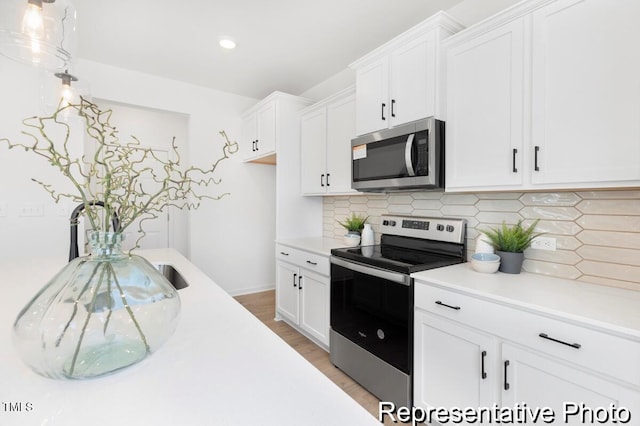 kitchen featuring white cabinets, light countertops, appliances with stainless steel finishes, and tasteful backsplash
