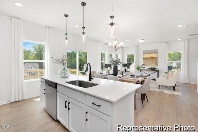 kitchen with a sink, stainless steel dishwasher, open floor plan, and light wood-style floors