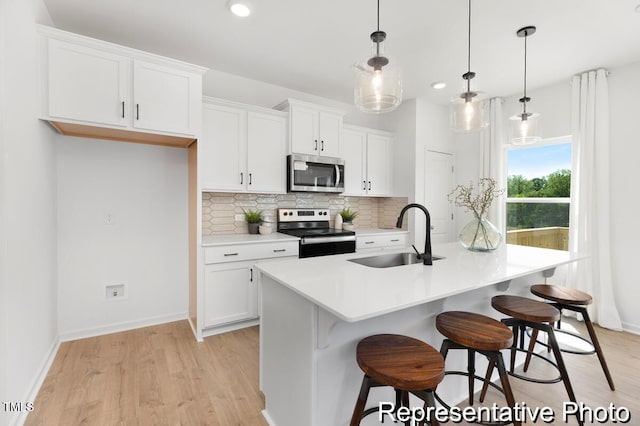 kitchen with a sink, decorative backsplash, stainless steel appliances, white cabinets, and light wood-type flooring