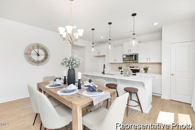 dining area featuring an inviting chandelier, baseboards, light wood-type flooring, and recessed lighting