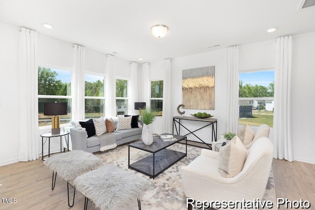 living room with a wealth of natural light, visible vents, and wood finished floors