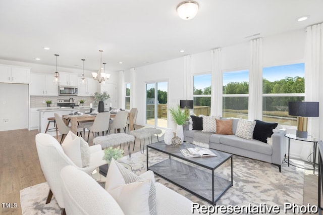 living area featuring a notable chandelier, light wood-style flooring, and recessed lighting