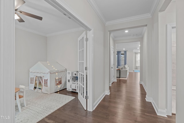 corridor with dark wood-type flooring, ornamental molding, and baseboards