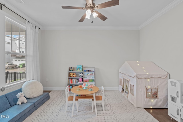 rec room featuring ornamental molding, ceiling fan, and baseboards